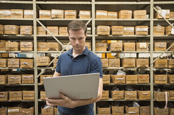 Caucasian worker using laptop in textile factory