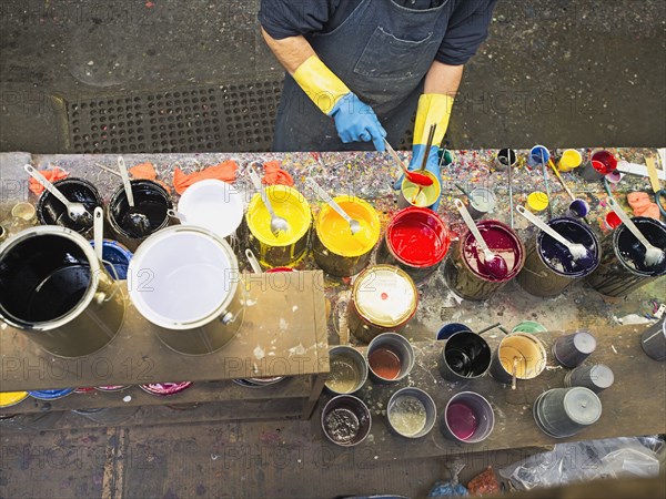 Hispanic worker mixing paint in workshop