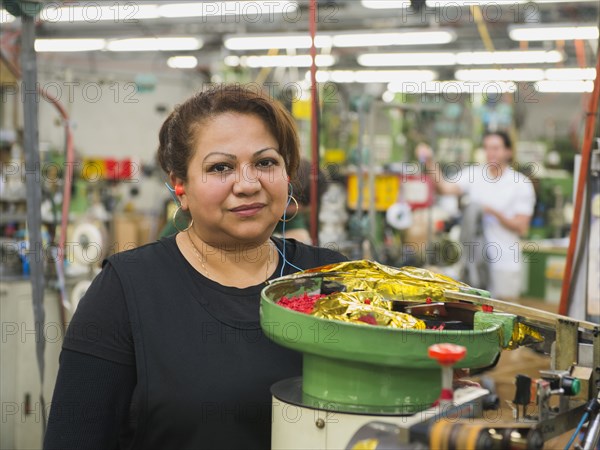 Hispanic worker operating machinery in textile factory