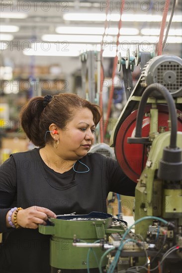 Hispanic worker operating machinery in textile factory