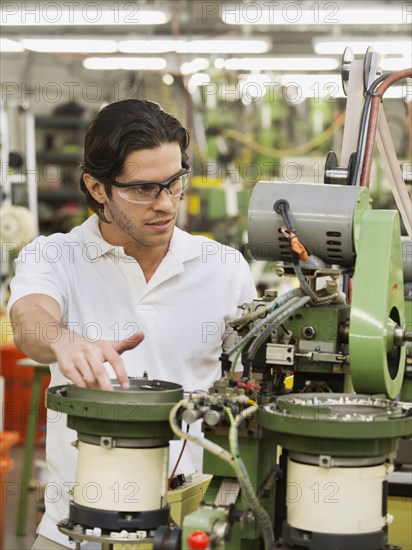 Mixed race worker operating machinery in textile factory