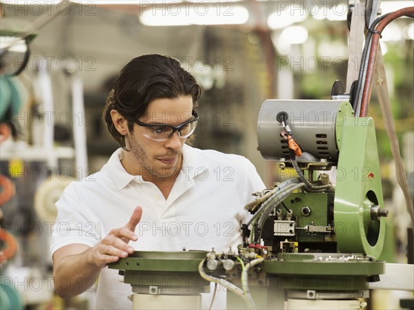 Mixed race worker operating machinery in textile factory