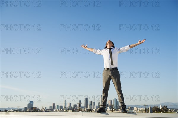Mixed race businessman standing on urban rooftop