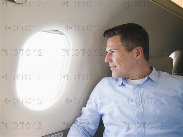 Caucasian businessman looking out airplane window