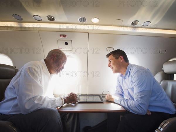 Businessmen talking on airplane