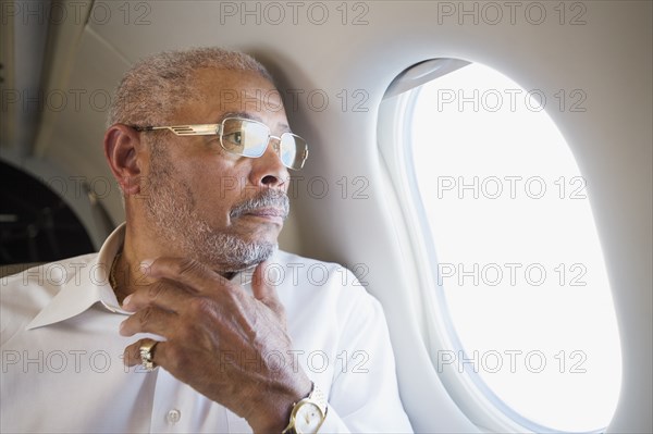 Black businessman looking out airplane window