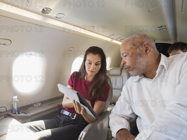 Business people using digital tablet on airplane