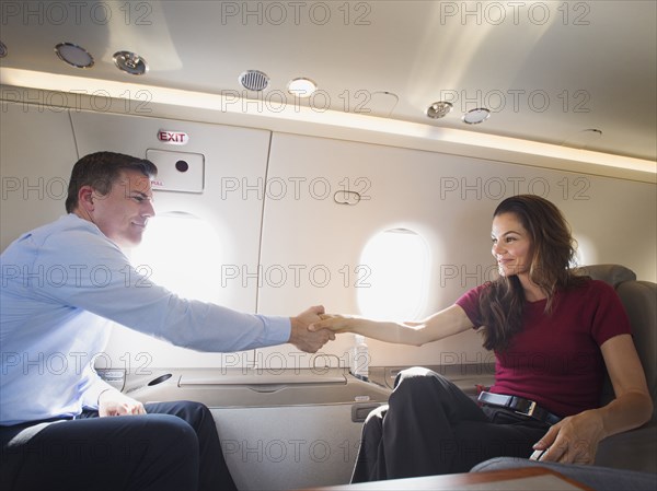 Business people shaking hands on airplane