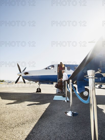 Business people disembarking airplane on runway