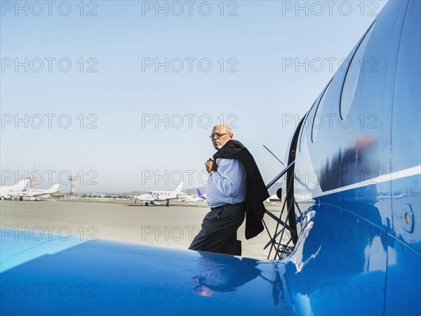 Black businessman leaving airplane on runway