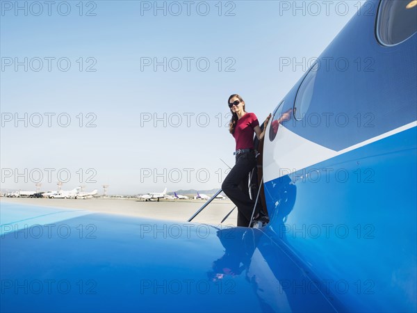 Mixed race businesswoman leaving airplane on runway