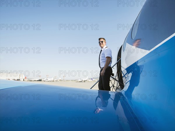 Caucasian pilot leaving airplane on runway