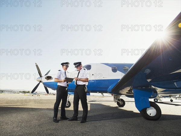 Caucasian pilots using digital tablet on runway