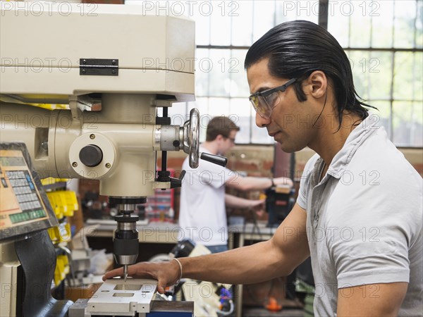 Workers using machinery in machine shop