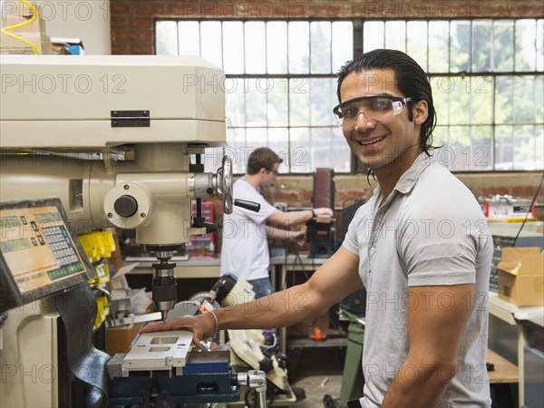 Workers using machinery in machine shop