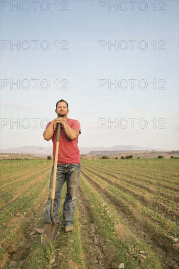 Caucasian farmer with shovel in crop field