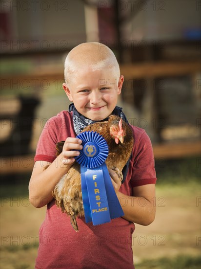 Caucasian boy with prize winning chicken on farm