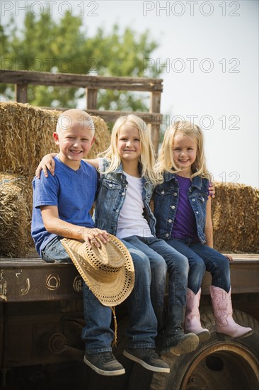 Caucasian children sitting on truck on farm