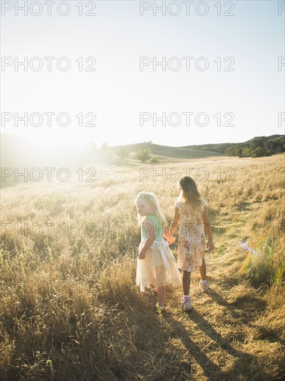 Caucasian girls holding hands in rural field