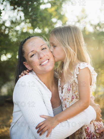 Girl kissing mother outdoors