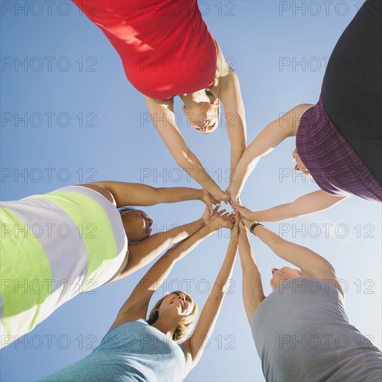 Women putting hands together outdoors