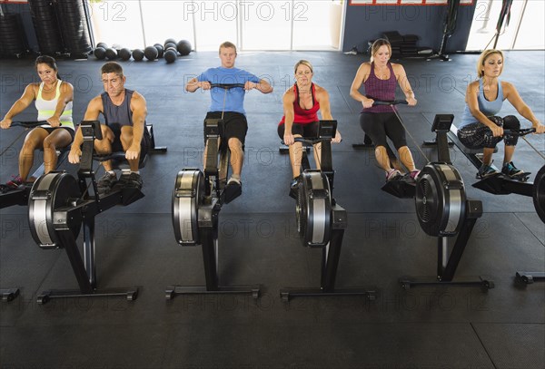 People using rowing machines in gym