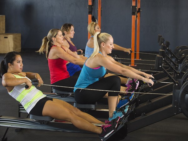 Women using rowing machines in gym