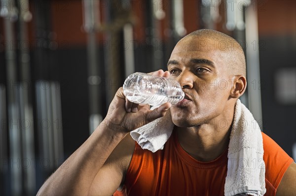 Black man drinking water in gym