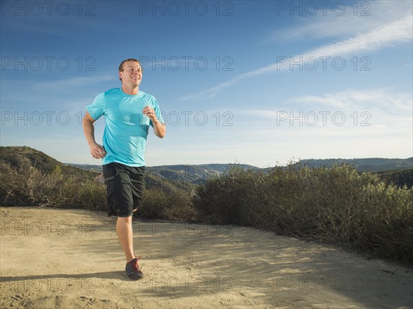 Caucasian man jogging on hilltop