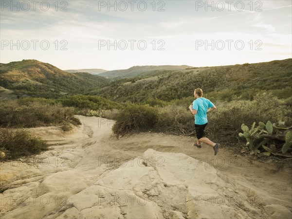 Caucasian man jogging on hilly path