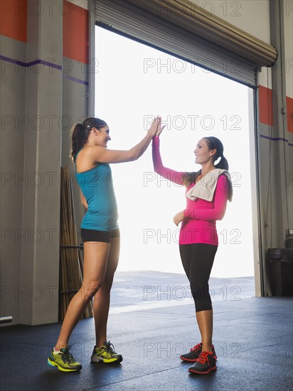 Caucasian women high fiving in gym