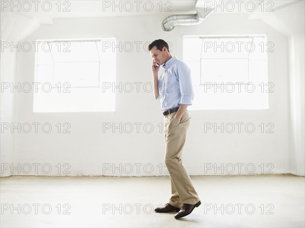 Caucasian businessman talking on cell phone in empty office