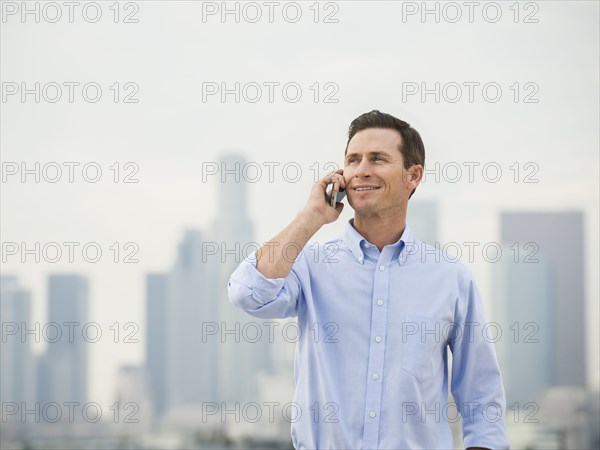 Caucasian businessman on cell phone on urban rooftop