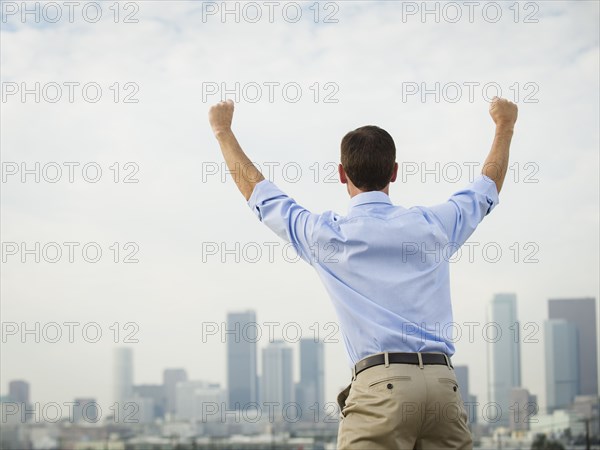 Caucasian businessman cheering on urban rooftop