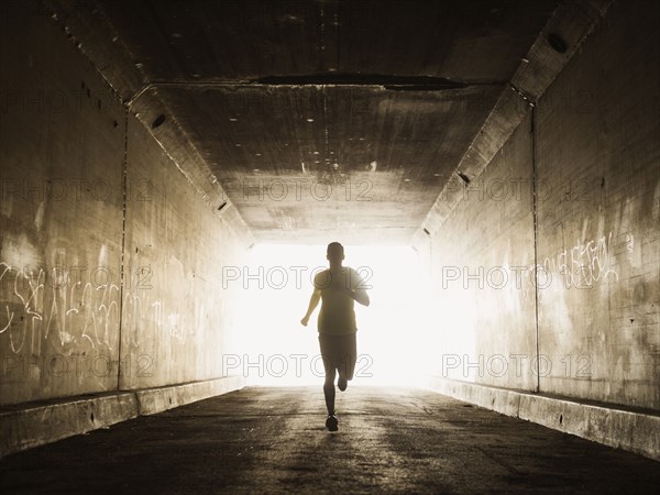 Caucasian man running in urban tunnel