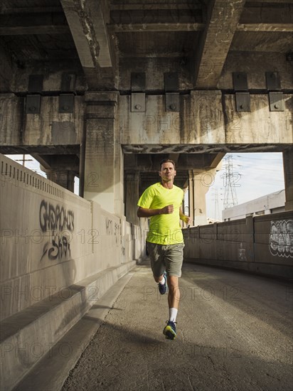 Caucasian man running in urban tunnel