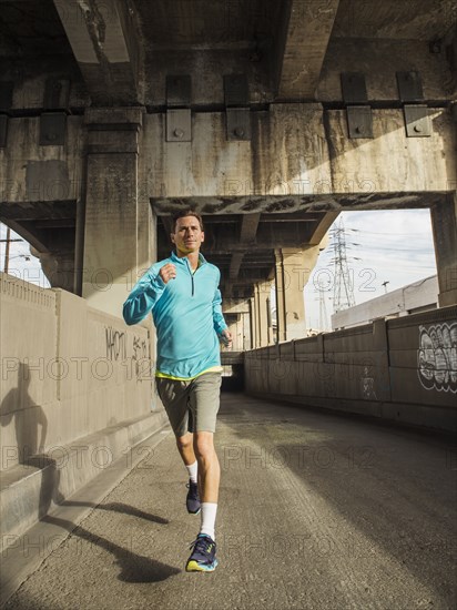 Caucasian man running in urban tunnel