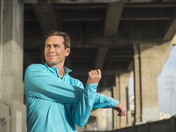 Caucasian man stretching in urban tunnel