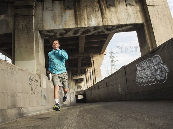 Caucasian man running in urban tunnel