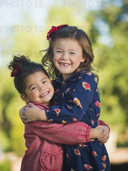 Mixed race girls hugging outdoors