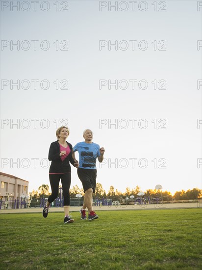 Older couple jogging together in urban park