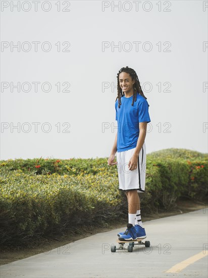 Black teenage boy riding skateboard on street