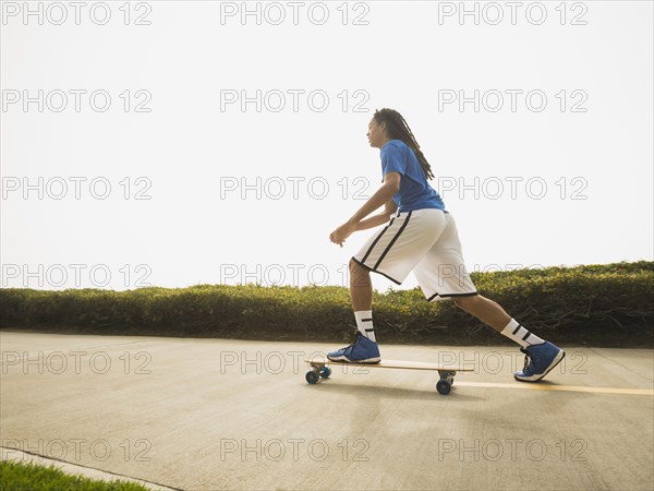 Black teenage boy riding skateboard on street
