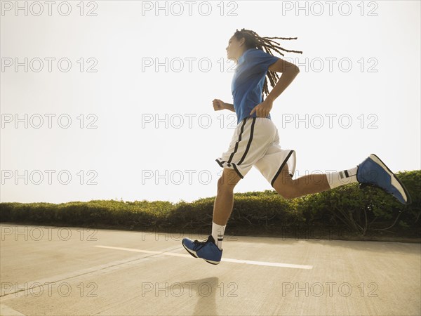 Black teenage boy running on street