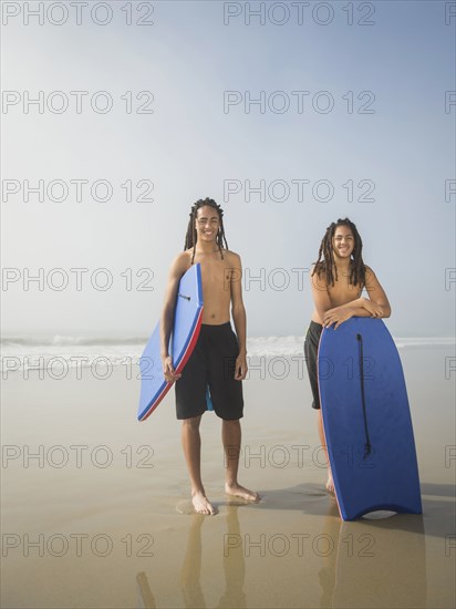 Black teenage boys with boogie boards on beach