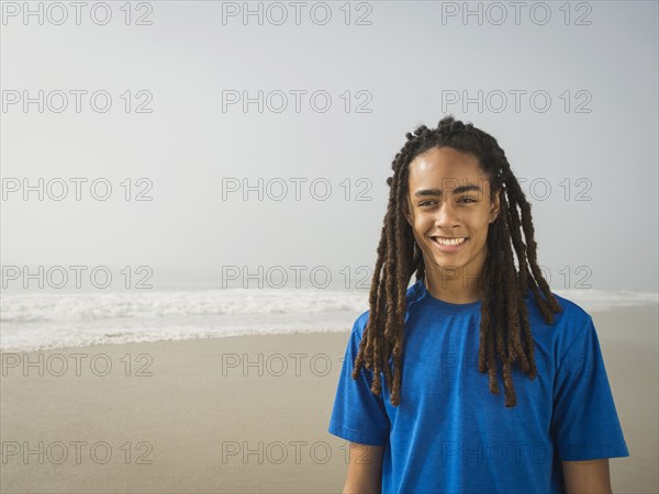 Black teenage boy smiling on beach