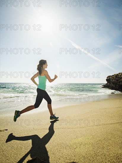 Caucasian woman running on beach