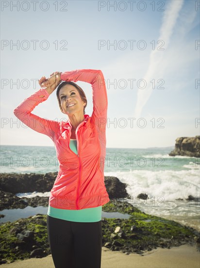 Caucasian runner stretching on beach