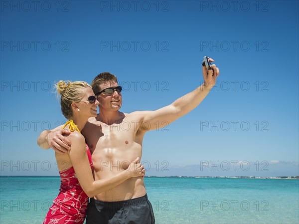 Caucasian couple taking selfie on tropical beach