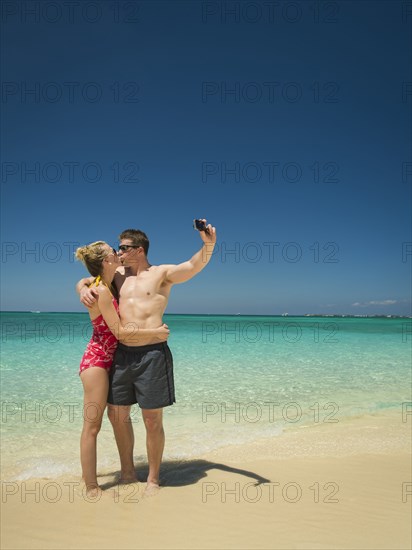 Caucasian couple taking selfie on tropical beach